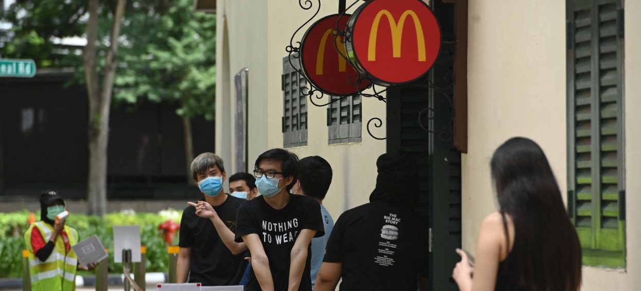 McDonald’s has adopted an emissions target in the region. The contractual power that franchisors have places them in a unique position to speedily transition many other businesses into low-emissions, more climate-friendly activity. In this picture, people wearing face masks queue outside a McDonald’s fast-food restaurant in Singapore on 11 May, 2020. (Photo: Roslan RAHMAN/ AFP)