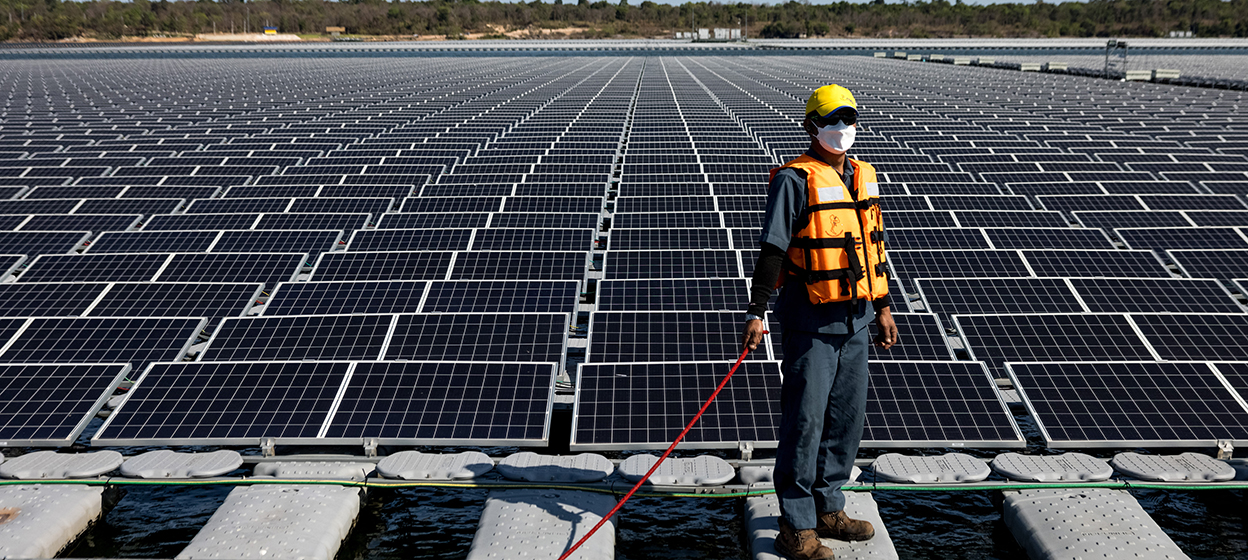 A worker stands beside floating solar panels
