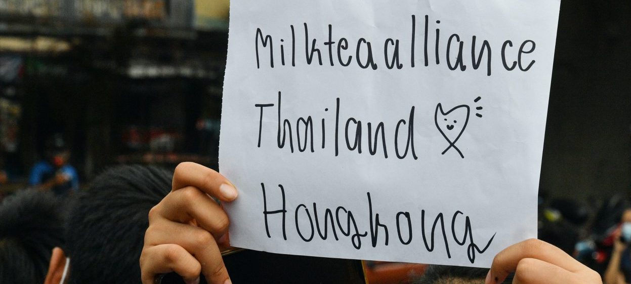 A pro-democracy protester holds up a sign relating to the "milk tea alliance" during an anti-government rally at Kaset intersection in Bangkok on October 19, 2020.