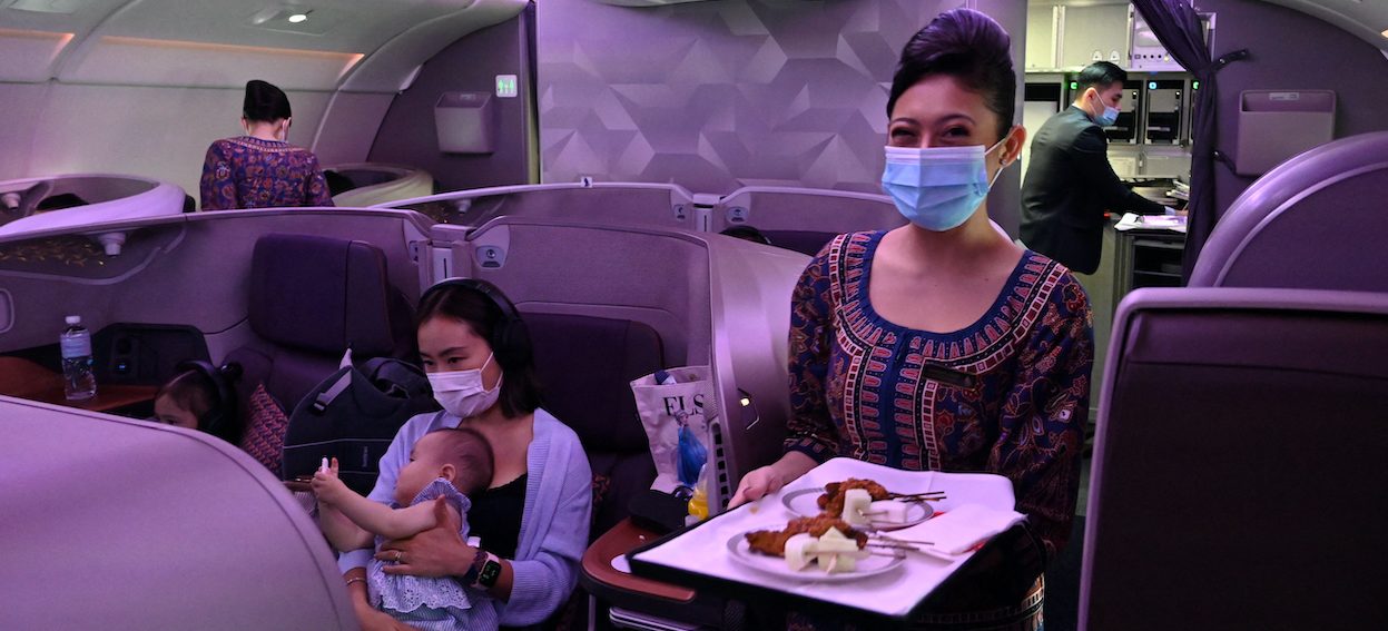 A Singapore Airlines stewardess smiles while serving food in business class during the inaugural lunch at Restaurant A380 at Changi onboard a Singapore Airlines Airbus A380 plane at Changi International Airport in Singapore on 24 October, 2020. Singapore and Zealand, two countries lauded for their pandemic responses, demonstrate how an intensified surveillance system for Covid-19 can work. (Photo: Roslan RAHMAN/ AFP)