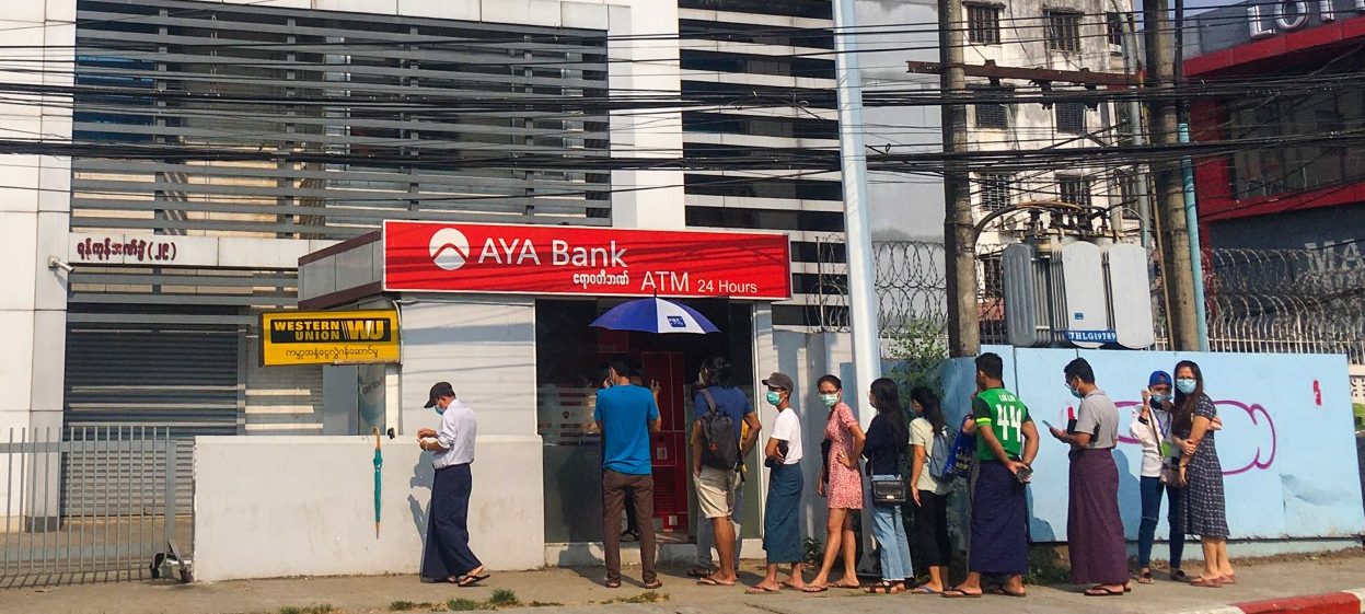 People queue as they wait to withdraw money from automated teller machines (ATM) of AYA Bank in Yangon on 18 March, 2021, amid strained banking operations due to the mass protests against the February military coup. (Photo: STR / AFP)