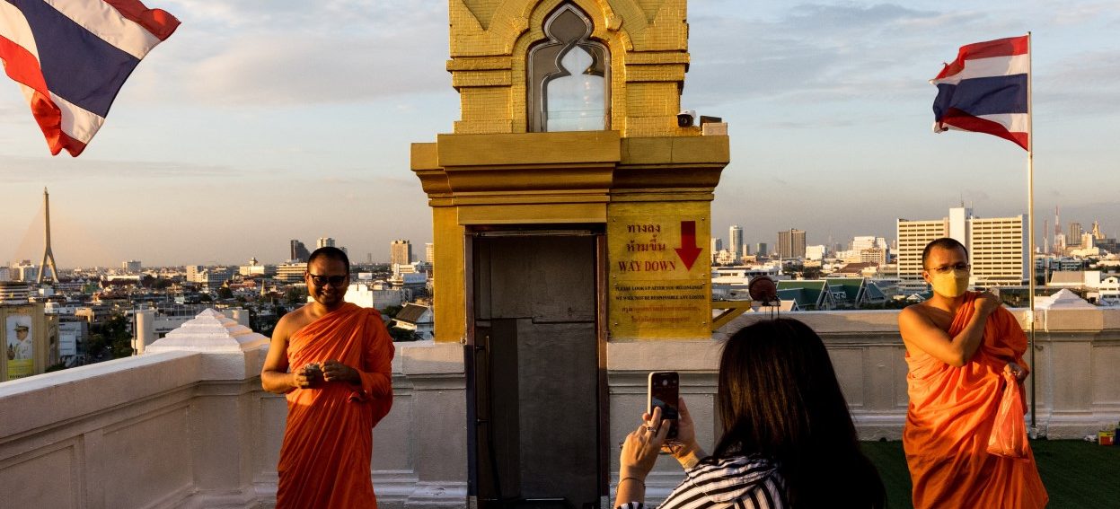 A Buddhist monk has his picture taken at Wat Saket temple as the sun sets in Bangkok on November 9, 2021. (Photo: Jack TAYLOR / AFP)