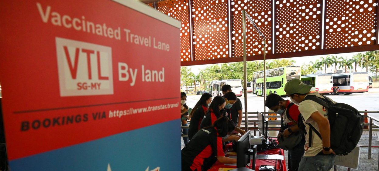 Passengers check-in over the counter in Singapore on 29 November, 2021 for crossing the border by bus through the vaccinated travel lane (VTL) between Singapore and Malaysia's southern state of Johor. (Photo: Roslan RAHMAN / AFP)