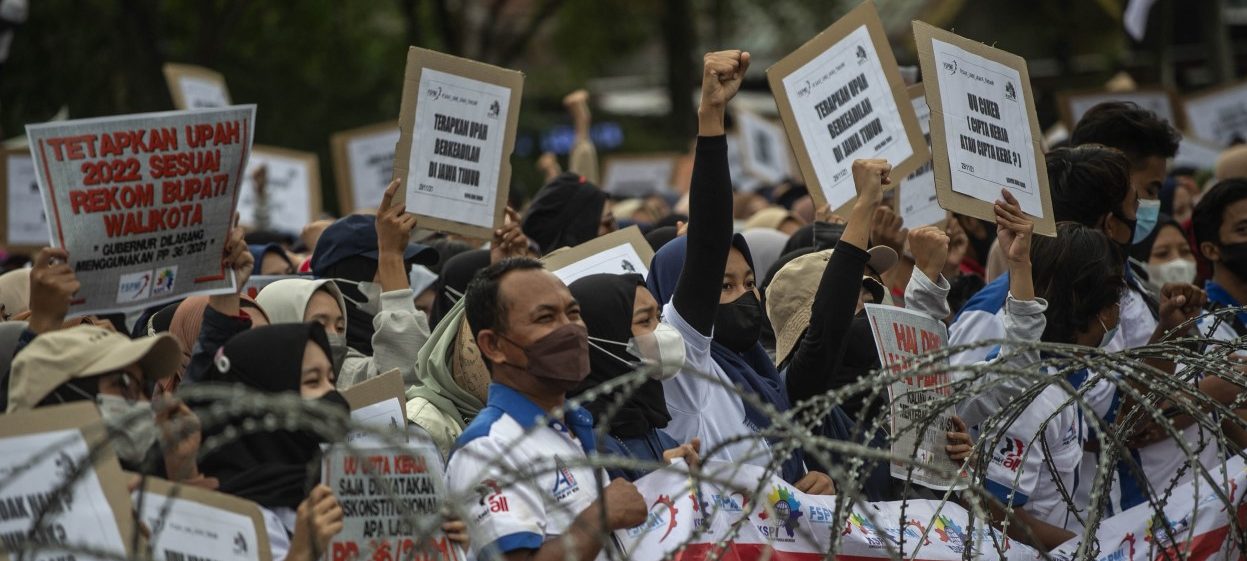 Labour activists hold placards during a protest against the government's controversial 'omnibus' or job creation law in Surabaya on November 29, 2021. (Photo: Juni Kriswanto / AFP)