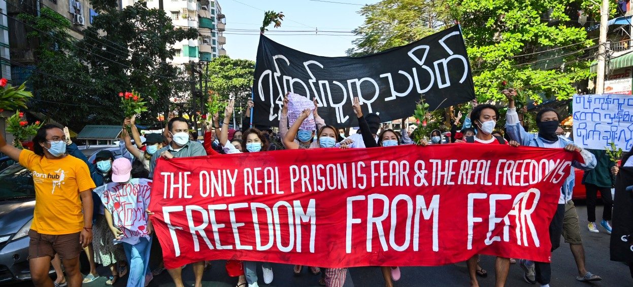 In this picture, protesters in Yangon hold banners as they participate in a demonstration on 5 December 2021 against the military coup which occurred on 1 February 2020. (Photo: STR/AFP)
