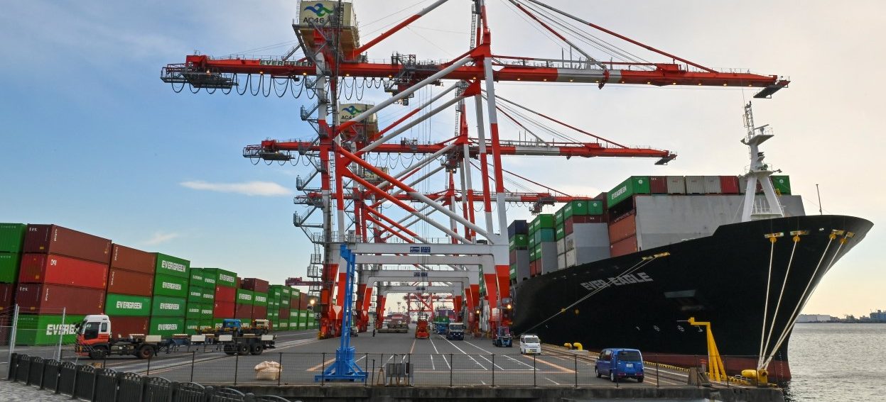 Large ship-to-shore cranes are used to load cargo containers off a ship and onto waiting trucks at the international cargo terminal at the port in Tokyo on 20 January, 2022. (Photo: Kazuhiro NOGI / AFP)