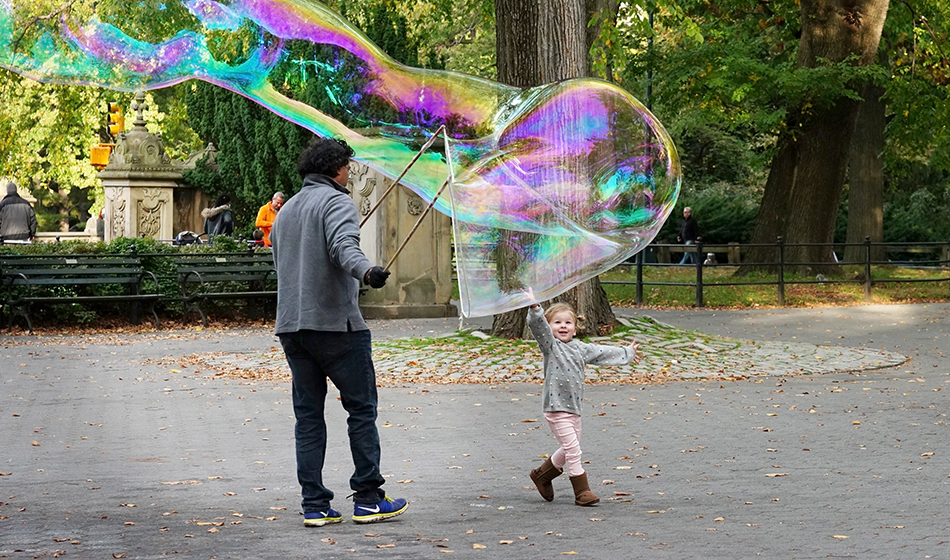 A child reaches for a giant bubble in Central Park