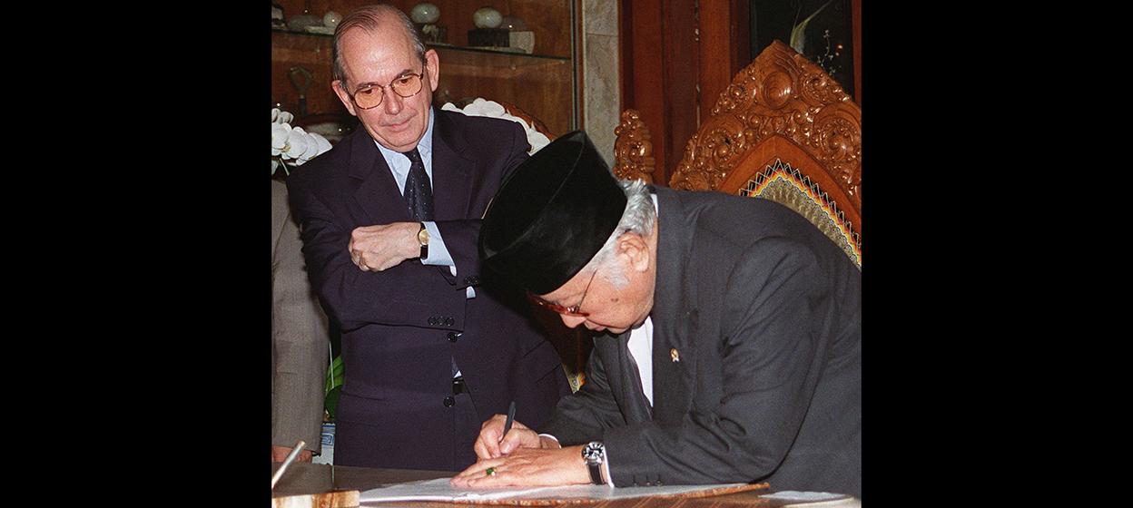 Indonesian President Suharto signs a new letter of agreement as IMF Director-General Michel Camdessus looks on