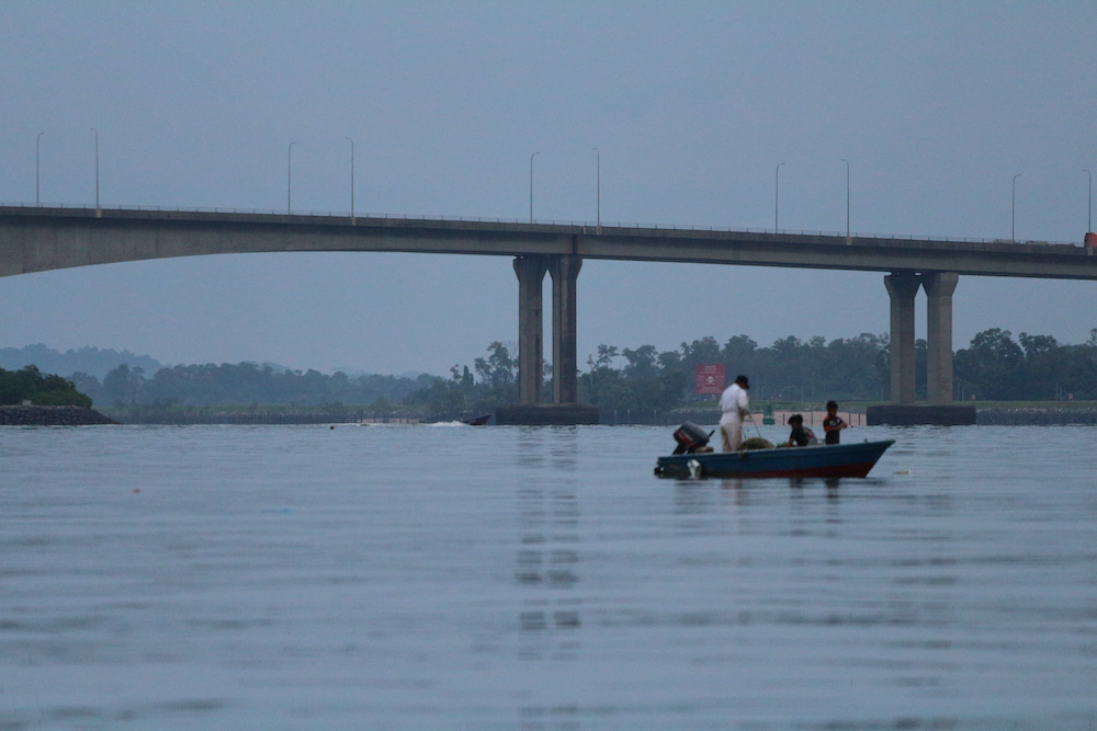 Groups dependent on fishing and agriculture reported an immediate loss of incomes due to a lack of Singaporean buyers and also due to local travel limits. In this picture, Johor’s artisanal fishermen checking their catch just under the now-empty Second Link bridge. (Photo: Serina RAHMAN/ ISEAS – Yusof Ishak Institute.)